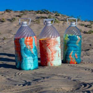 Three rinse water jugs in the sand